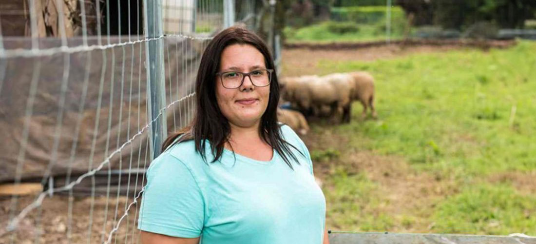 Bild von einer Frau mit Zaun und Tieren im Hintergrund